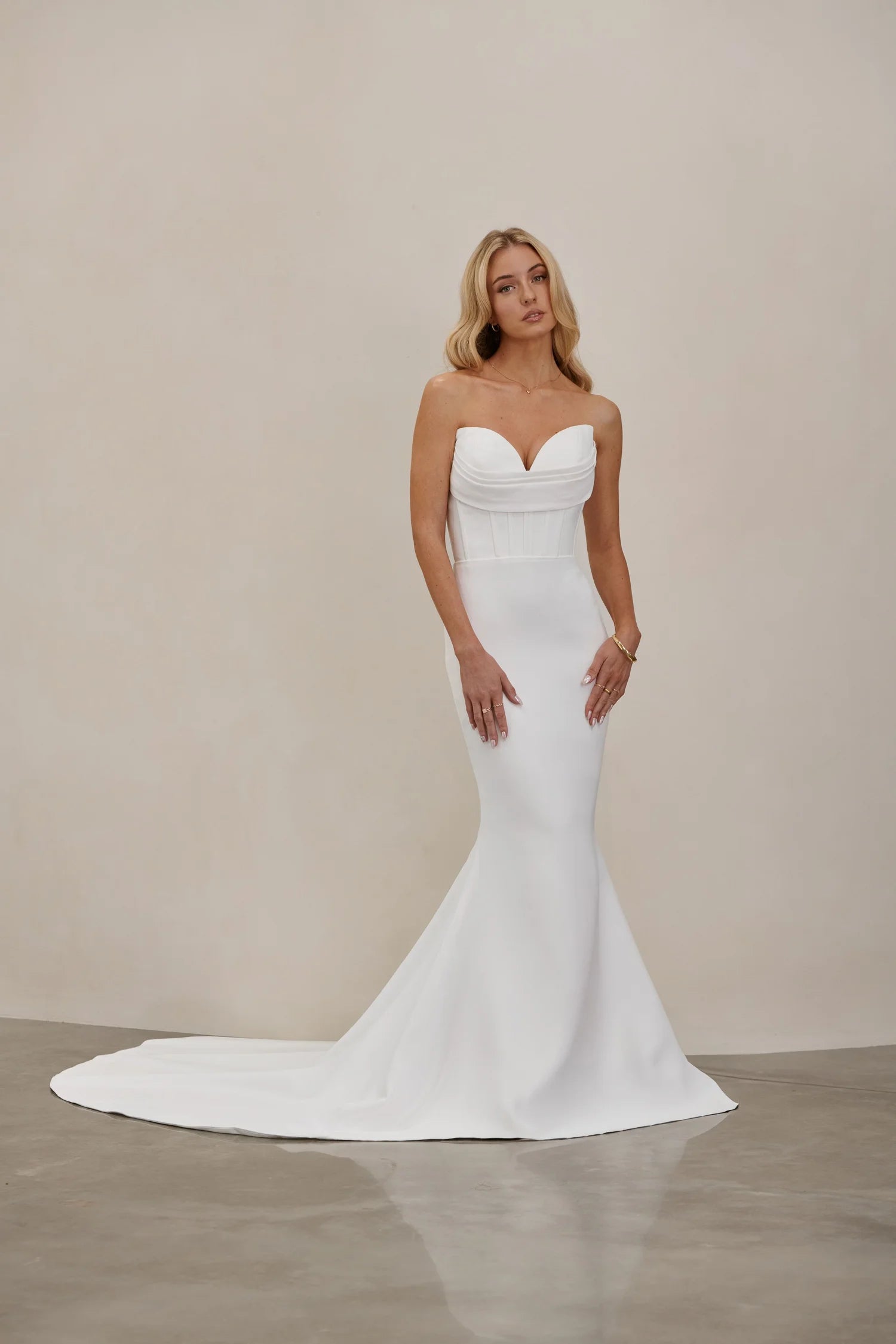 Woman wearing an after five crepe mermaid wedding dress against a plain background