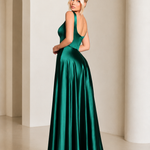 Woman in a green evening gown standing in a softly lit room with arches.