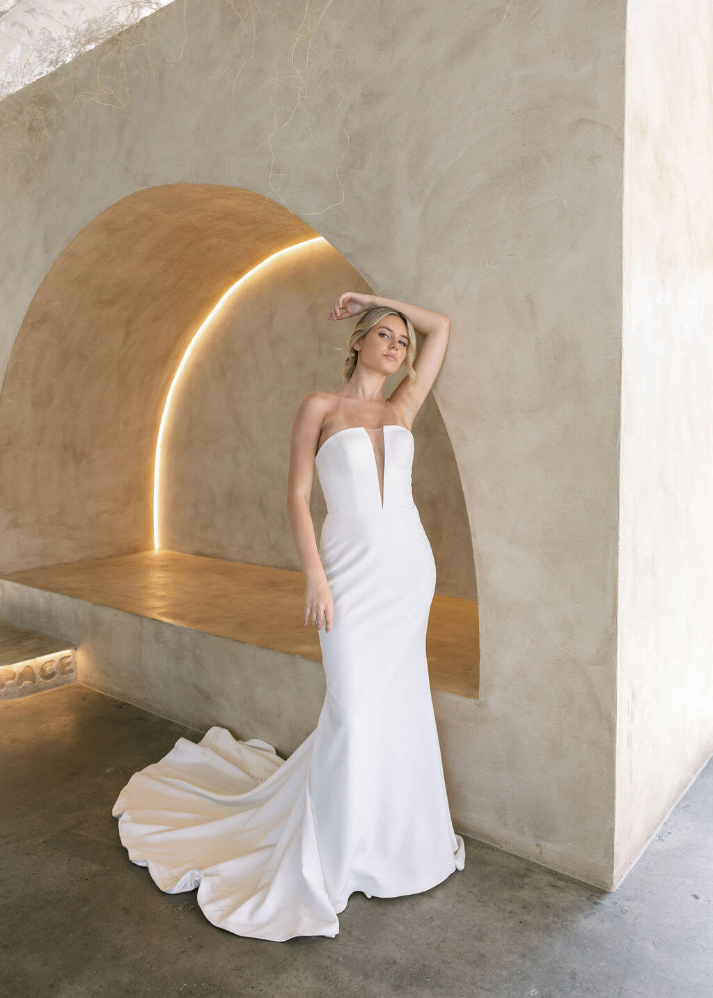 Woman in a modern crepe fit-and-flare wedding dress standing against a modern architectural background