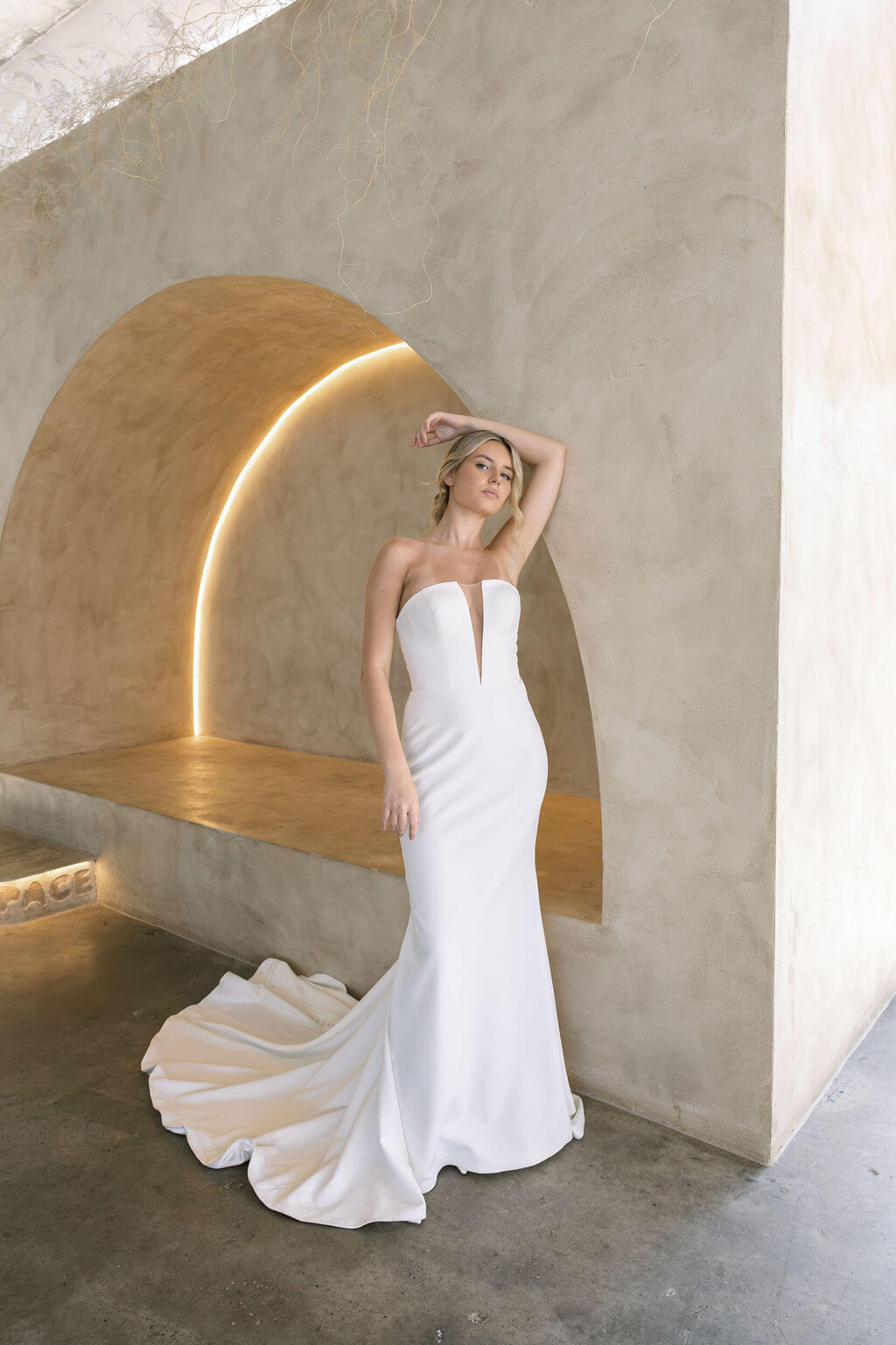 Woman in a modern crepe fit-and-flare wedding dress standing against a modern architectural background
