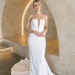 Woman in a modern crepe fit-and-flare wedding dress standing in a modern architectural setting.