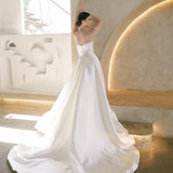 Woman in a white Vermont Mikado wedding dress standing in a modern indoor setting with light-colored walls.