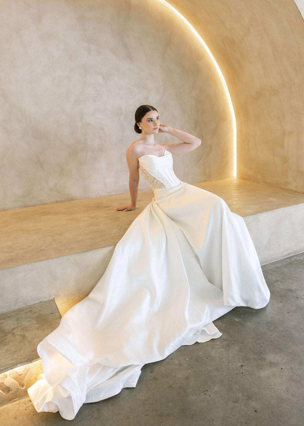 Woman in a white Vermont Mikado wedding dress sitting on a modern architectural bench.