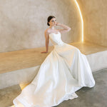 Woman in a white Vermont Mikado wedding dress sitting on a modern architectural bench.