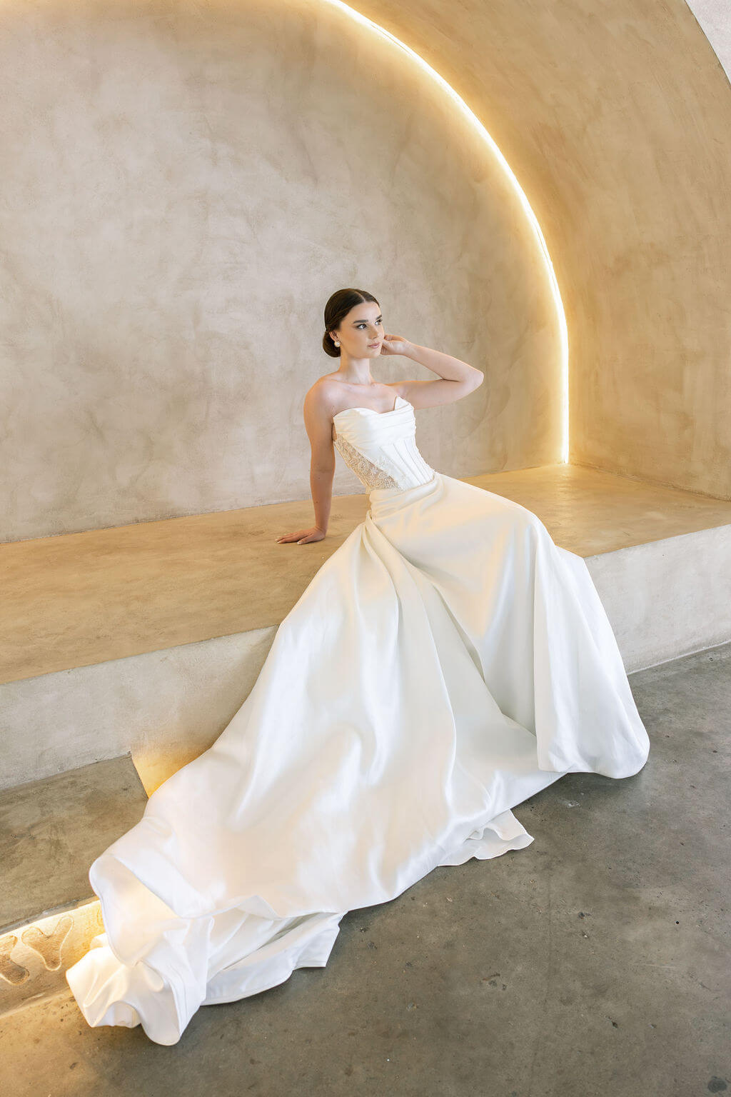 Woman in a white Vermont Mikado wedding dress sitting on a modern architectural bench.