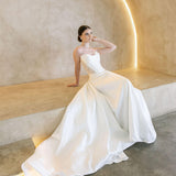 Woman in a white Vermont Mikado wedding dress sitting on a modern architectural bench.