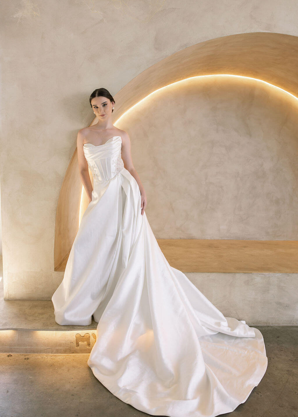 Woman in a white Vermont Mikado wedding dress standing against a modern architectural background