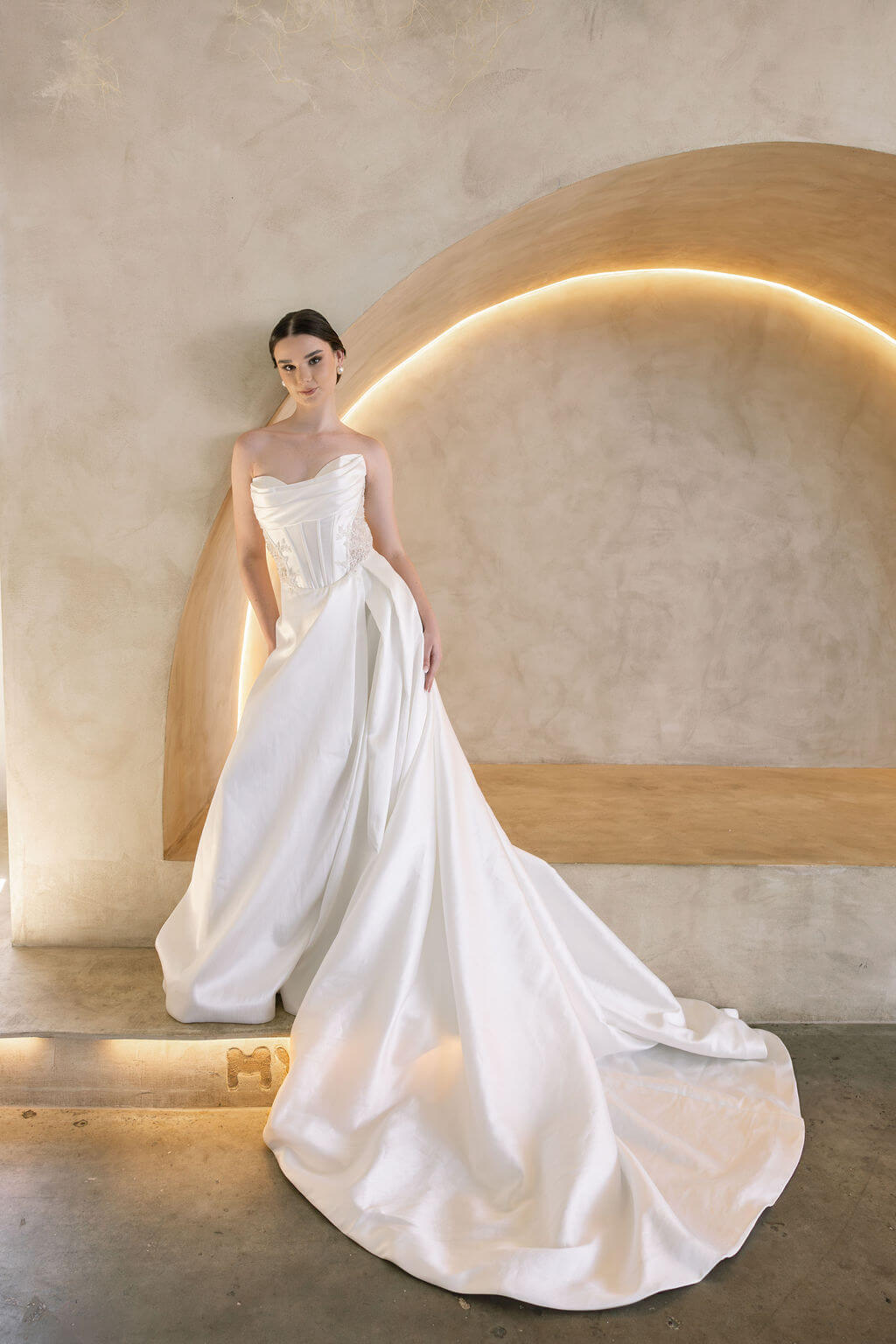 Woman in a white Vermont Mikado wedding dress standing against a modern architectural background