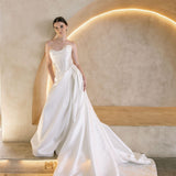 Woman in a white Vermont Mikado wedding dress standing against a modern architectural background