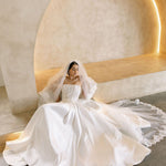 Bride wearing the Viena satin A-line wedding dress with lace corset bodice and flowing skirt.