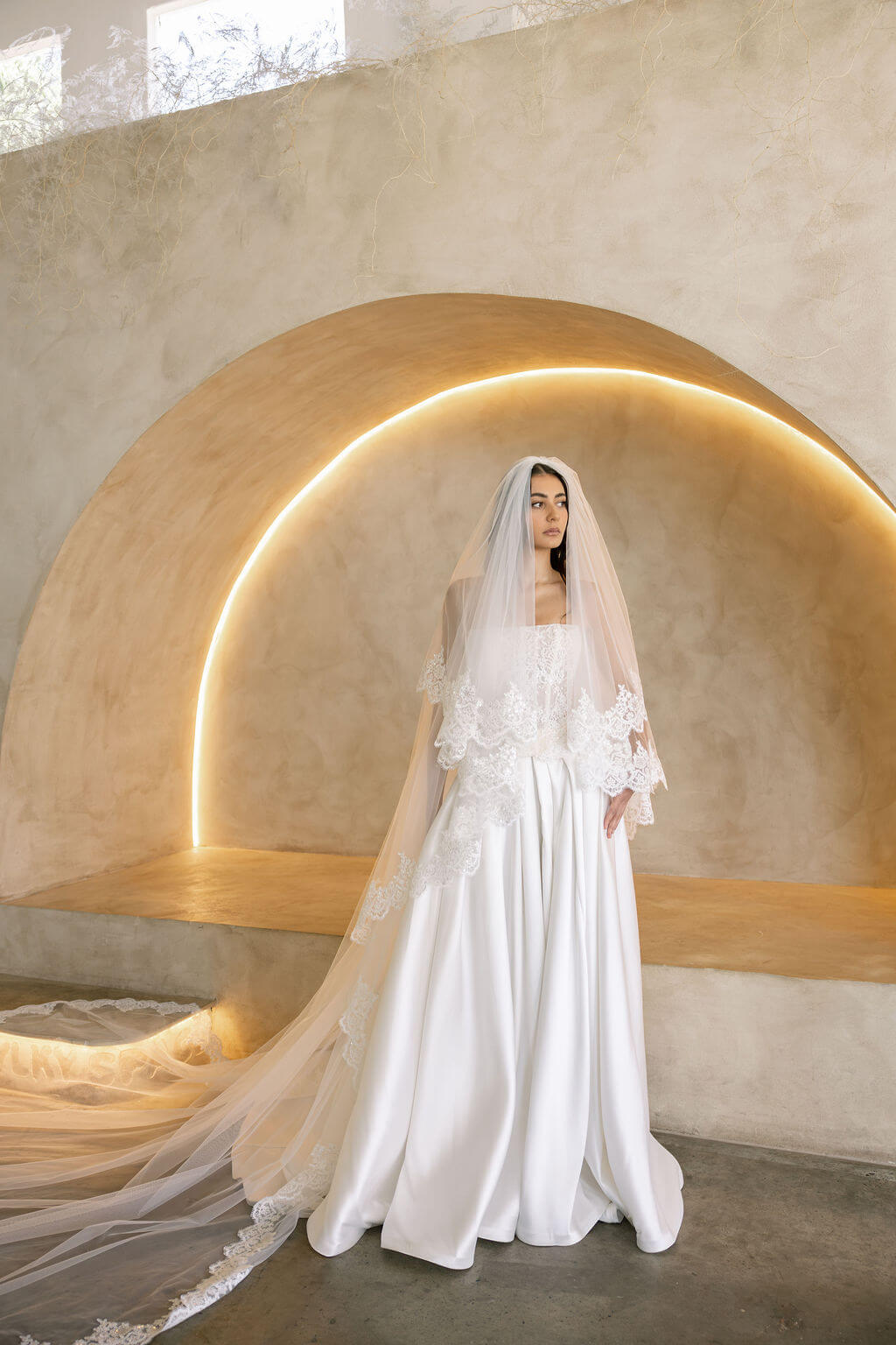 Bride wearing the Viena satin A-line wedding dress with lace corset bodice and long lace veil.