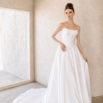Woman wearing a modern mikado wedding dress in a minimalistic room.