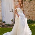 Winona boho tulle A-line wedding dress with beaded bodice and flowing layered skirt walking outside.