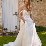 Winona boho tulle A-line wedding dress with beaded bodice and flowing layered skirt walking outside.