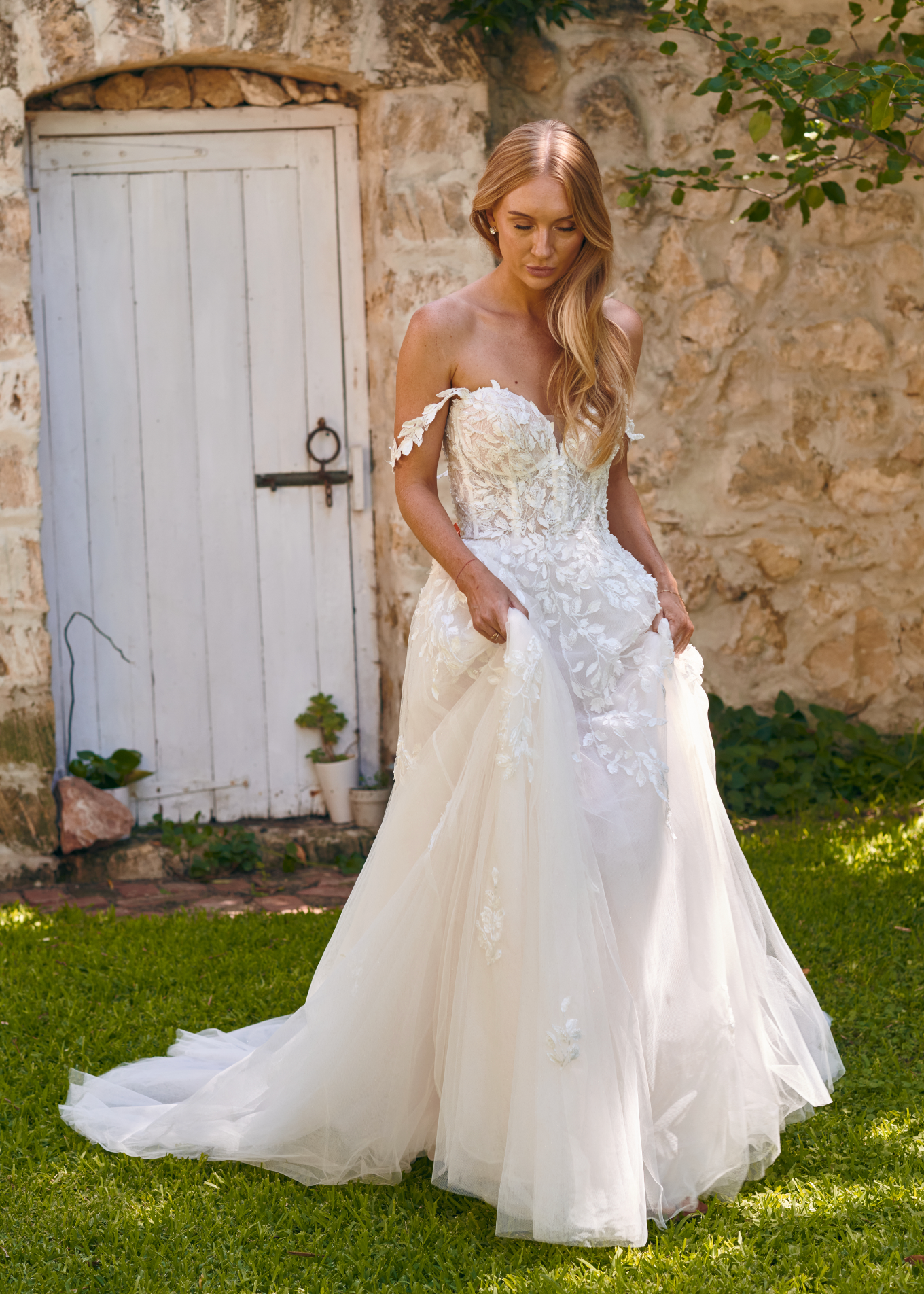 Winona boho tulle A-line wedding dress with beaded bodice and flowing layered skirt walking outside.