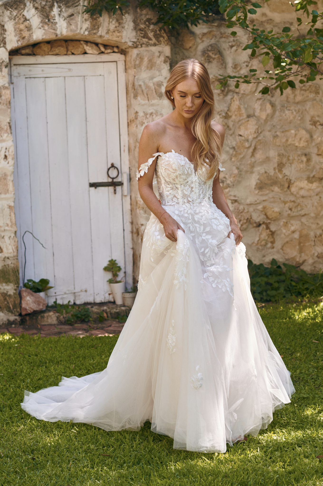 Winona boho tulle A-line wedding dress with beaded bodice and flowing layered skirt walking outside.