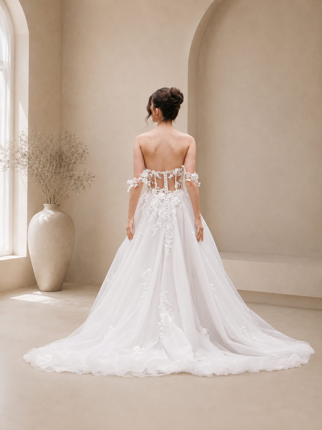 Woman in a white Wren floral lace wedding dress standing in a room with beige walls and a vase.