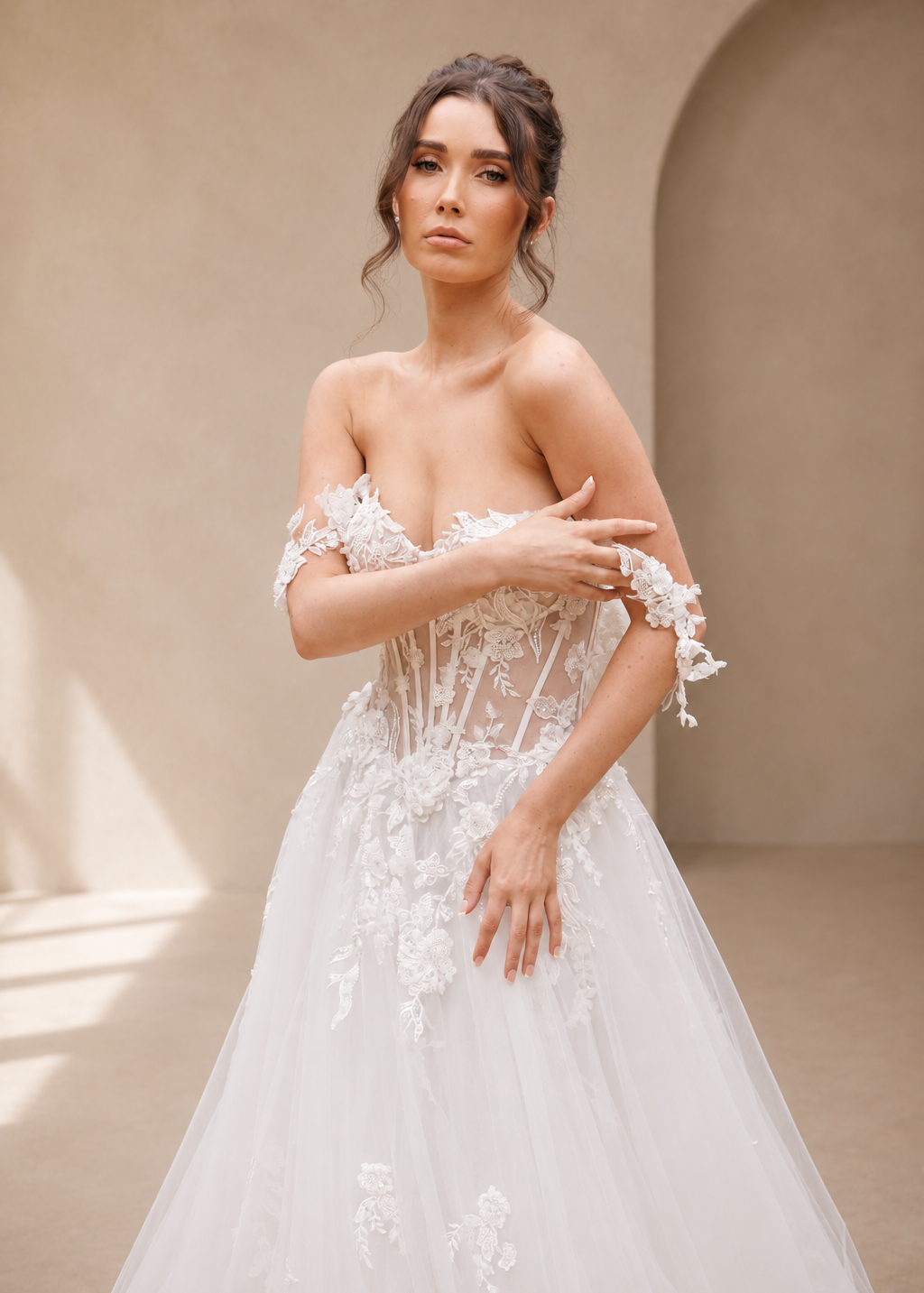 Woman wearing a white lWren floral lace wedding dress against a beige wall.