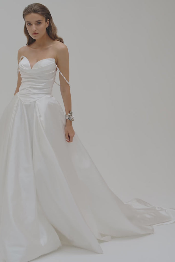 Bride wearing a duchess satin basque waist wedding dress on a plain white backdrop