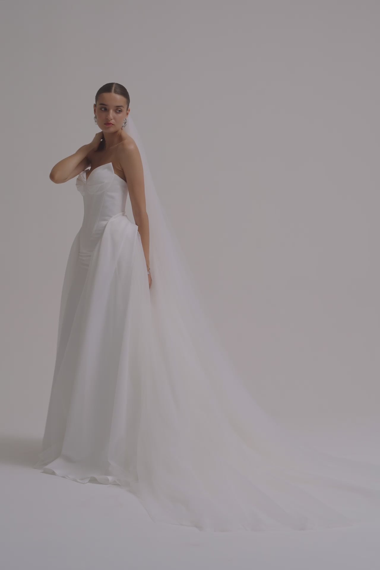 A bride wearing a strapless Duchess satin fitted wedding dress.